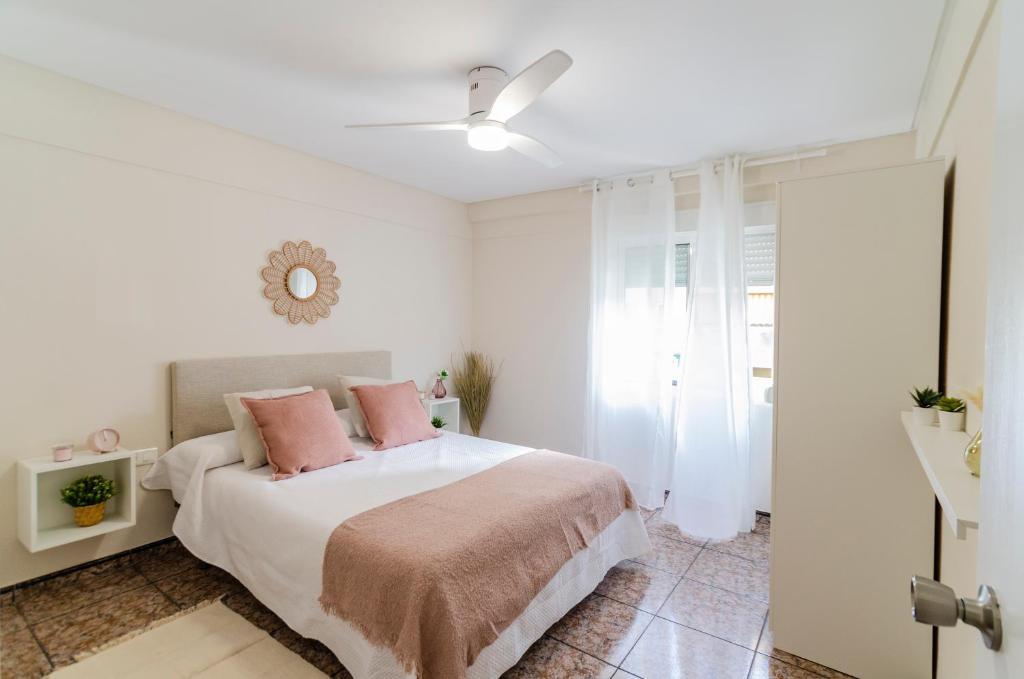 a white bedroom with a bed with pink pillows at LAS VEGAS CENTRO- HOME RENt MALAGA in Torre del Mar