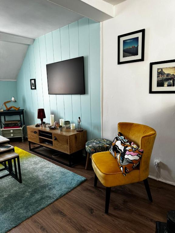 un salon avec une chaise et une télévision dans l'établissement Chez Suzie, au Tréport