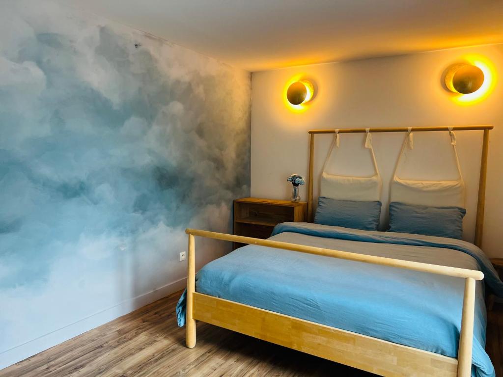- une chambre dotée d'un lit avec des draps bleus et un mur dans l'établissement La grande maison de la campagne, au pieds des Pyrénées Ariégeoises, à Arignac