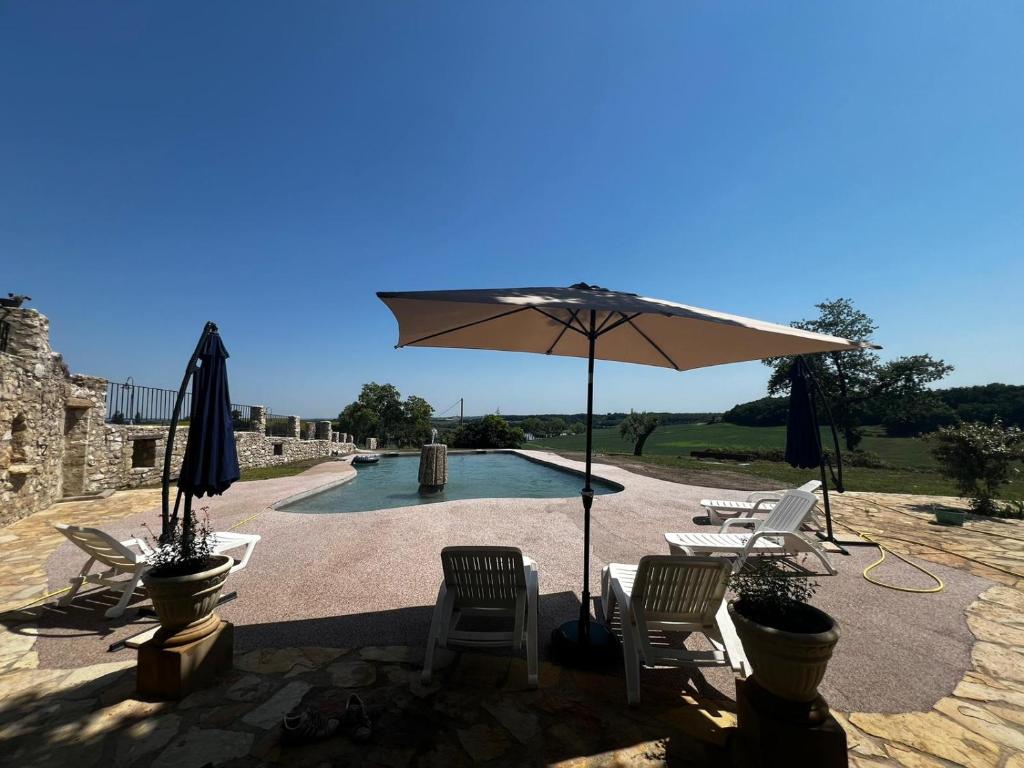 une terrasse avec des chaises et un parasol ainsi qu'une piscine dans l'établissement Chez Candice et Pascal gîte 1, à Lauraët