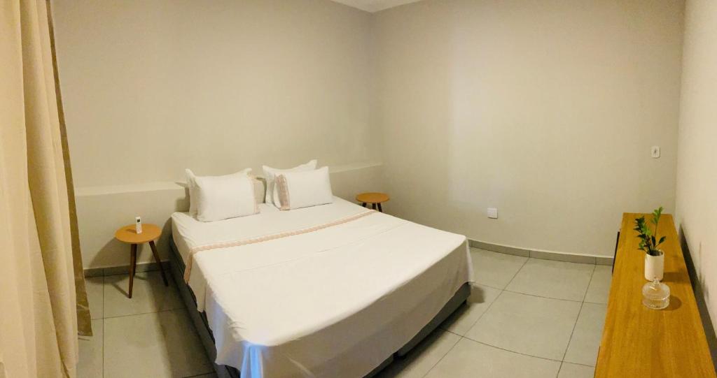 a bedroom with a white bed with white sheets and pillows at Suíte Privilegiada in Delfinópolis
