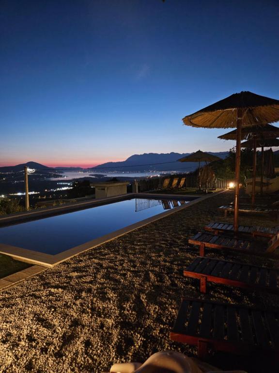 a swimming pool with chairs and an umbrella on a beach at Apartment Macic Dub II in Kotor