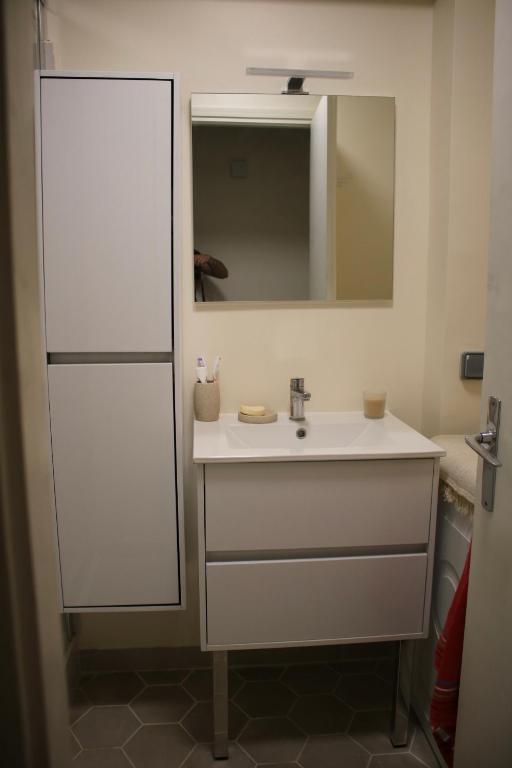 une salle de bain avec un lavabo blanc et un miroir dans l'établissement Chez Toni, à Asnières-sur-Seine