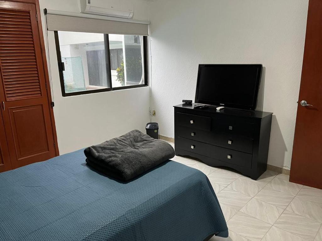 a bedroom with a bed and a tv on a dresser at Disfruta Boca del Rio in Boca del Río