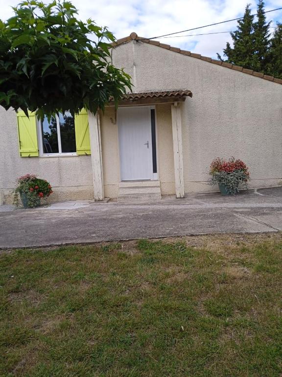 un bâtiment avec une porte blanche et deux plantes dans l'établissement Maison de vacance 3 chambres, à Cailhavel