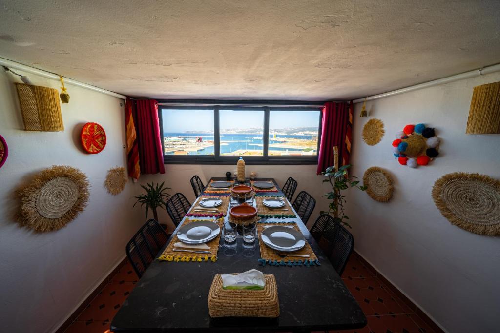 ein Esszimmer mit einem langen Tisch und einem großen Fenster in der Unterkunft Dar Sekka in Tangier
