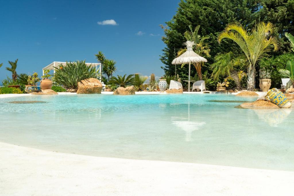 a large pool of blue water with chairs and trees at Casa Vacanze Verdemare con Piscina in Ribera