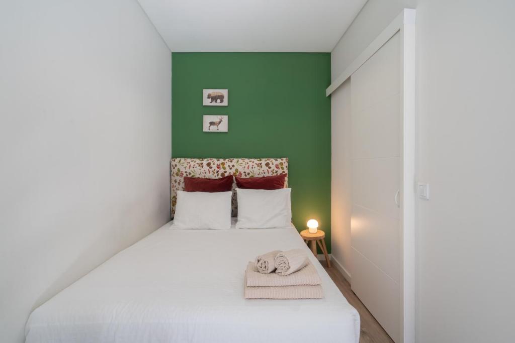 una camera con un letto bianco e una parete verde di Oporto Seaside Village - Casa Bosque a Matosinhos