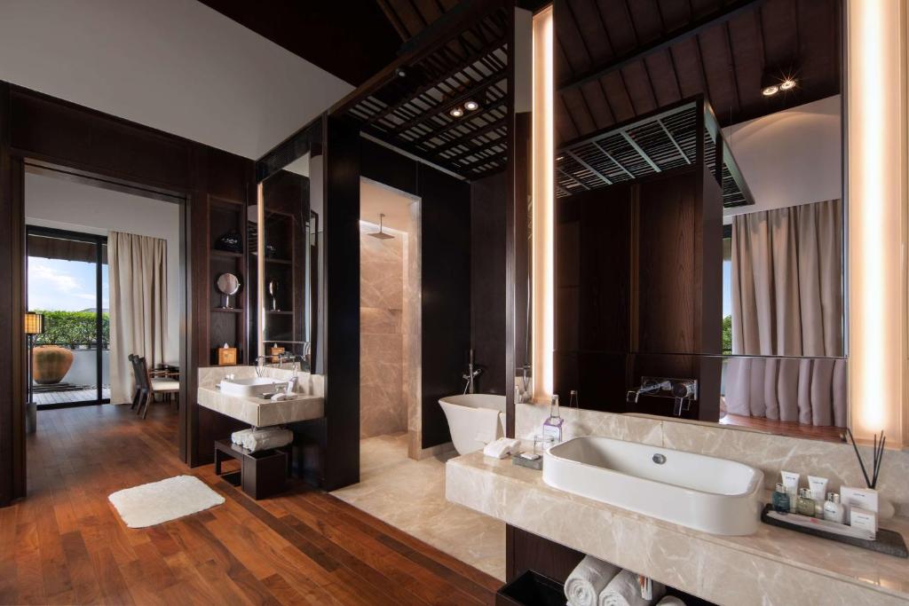 a bathroom with two sinks and a large mirror at Radisson Blu Bali Uluwatu in Uluwatu