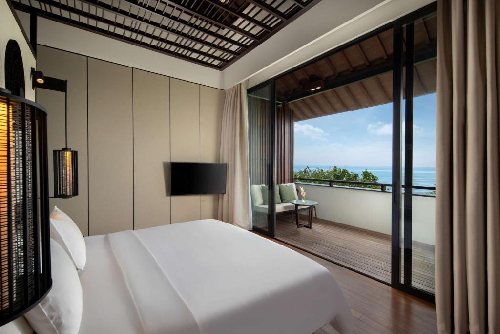 a bedroom with a bed and a view of the ocean at Radisson Blu Bali Uluwatu in Uluwatu