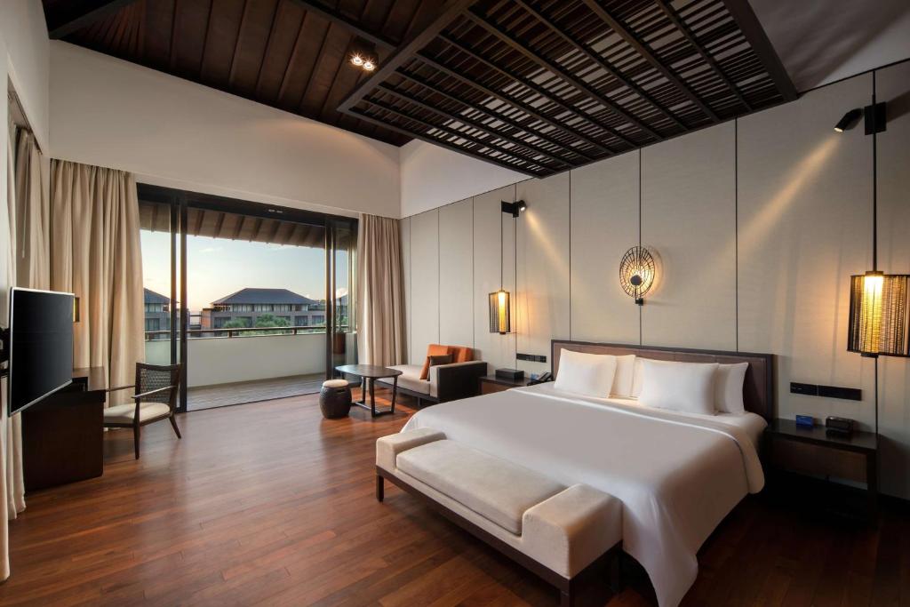 a bedroom with a large bed and a living room at Radisson Blu Bali Uluwatu in Uluwatu