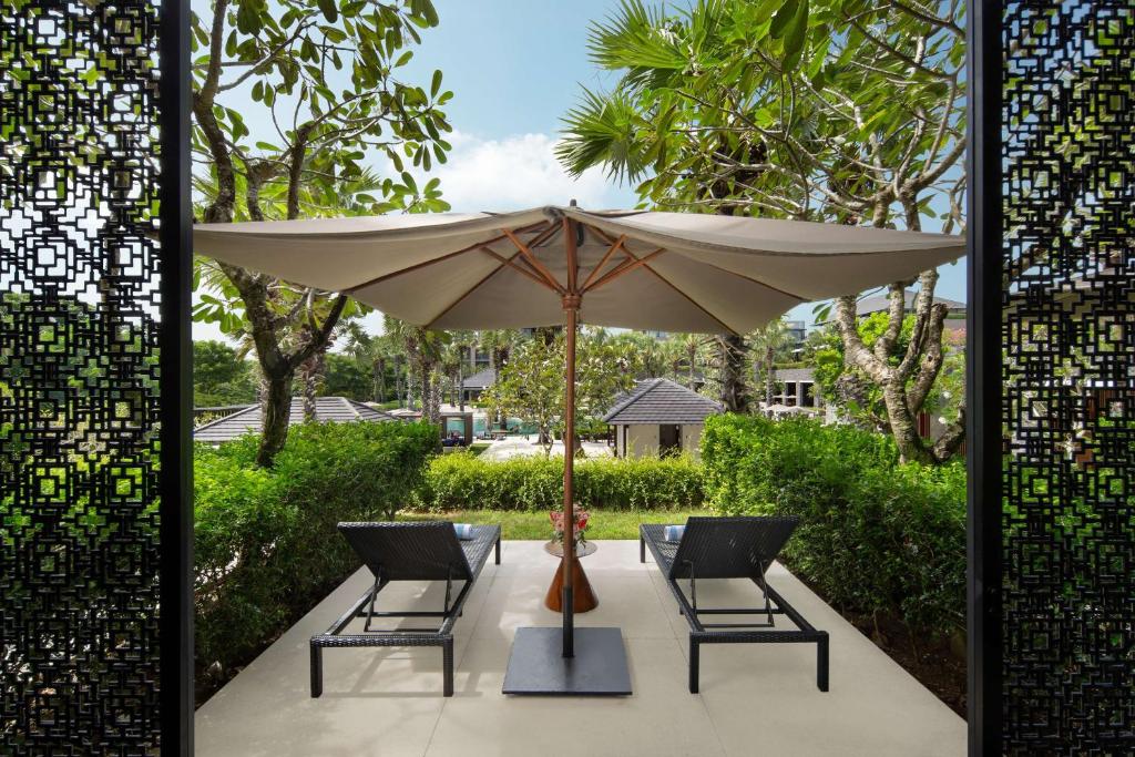 a patio with two chairs and an umbrella at Radisson Blu Bali Uluwatu in Uluwatu
