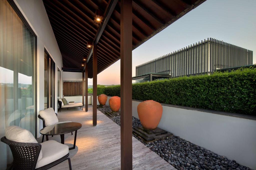 a patio with chairs and tables on a building at Radisson Blu Bali Uluwatu in Uluwatu