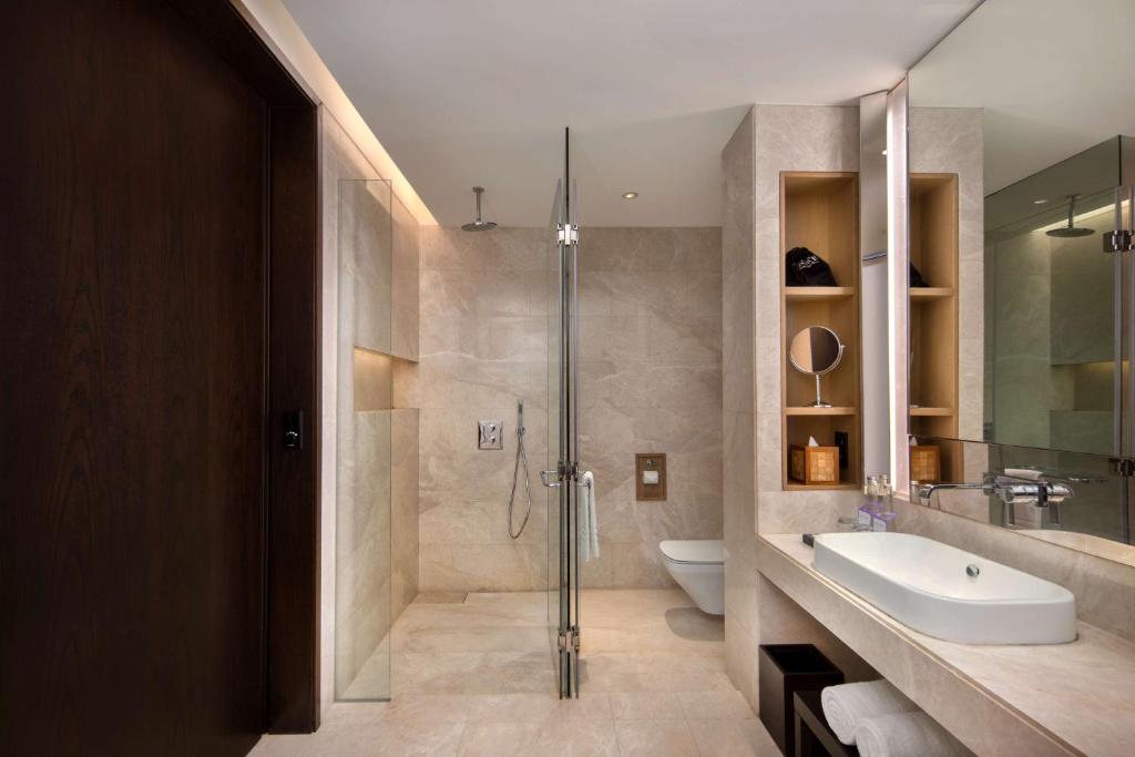 a bathroom with a shower and a sink and a toilet at Radisson Blu Bali Uluwatu in Uluwatu