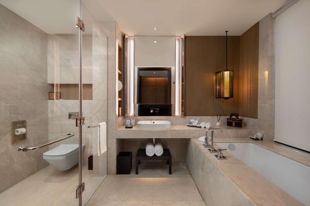 a bathroom with a tub and a sink and a toilet at Radisson Blu Bali Uluwatu in Uluwatu