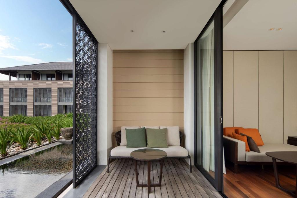 a balcony with a table and chairs and a pool at Radisson Blu Bali Uluwatu in Uluwatu