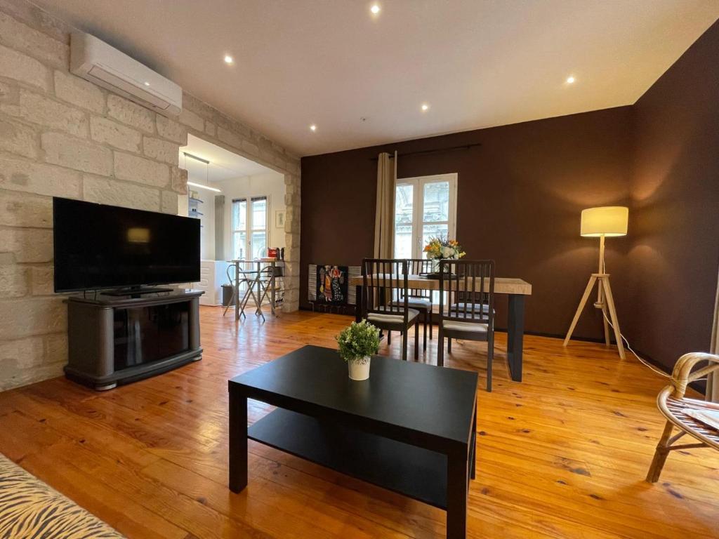 - un salon avec une télévision, une table et un canapé dans l'établissement Chaleureux Vernet - Terrasse - Clim - Hypercentre, à Avignon