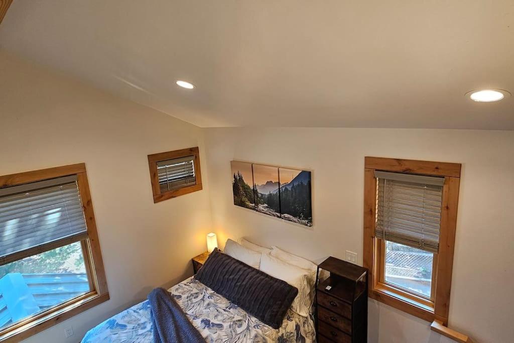 a bedroom with a bed and two windows at Beautiful Riverfront Near Mt Bachelor with Hot Tub in Bend