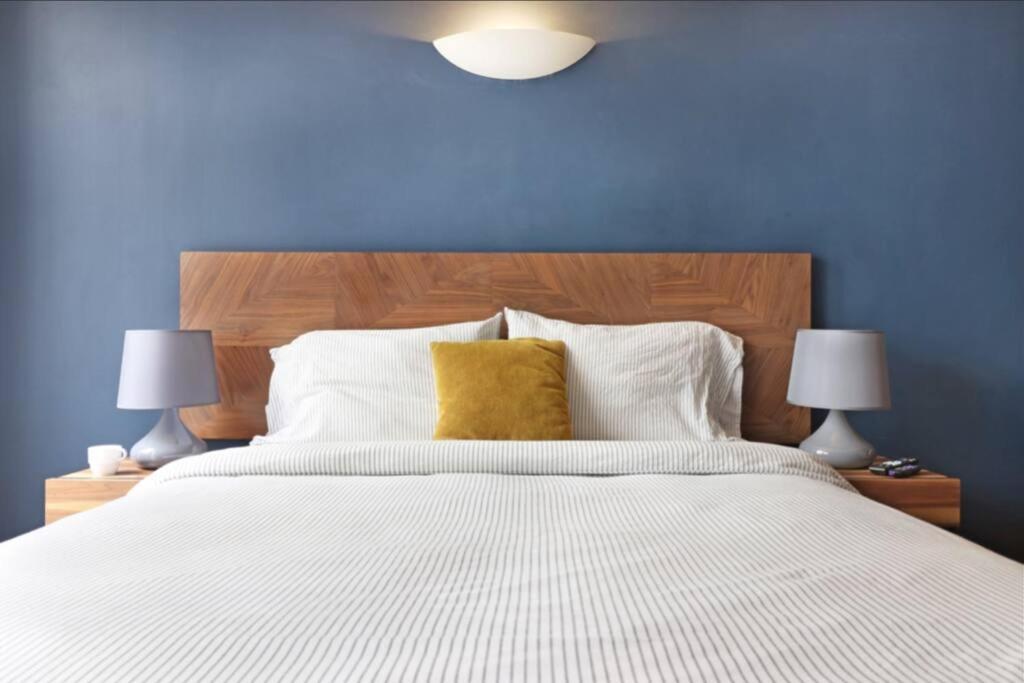 a blue bedroom with a large bed with a yellow pillow at DOWNTOWN APT Pool & Gym in Mexico City