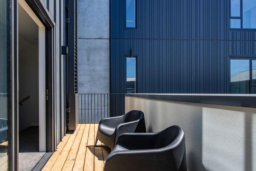 Una fila de sillas en un balcón con un edificio. en 2024 Townhouse, en Christchurch