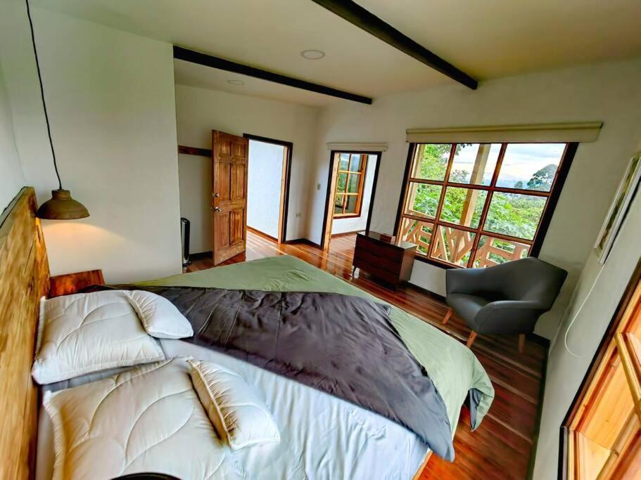 a bedroom with a bed and a chair and windows at Espectacular casa Campestre con Jacuzzi in Salento