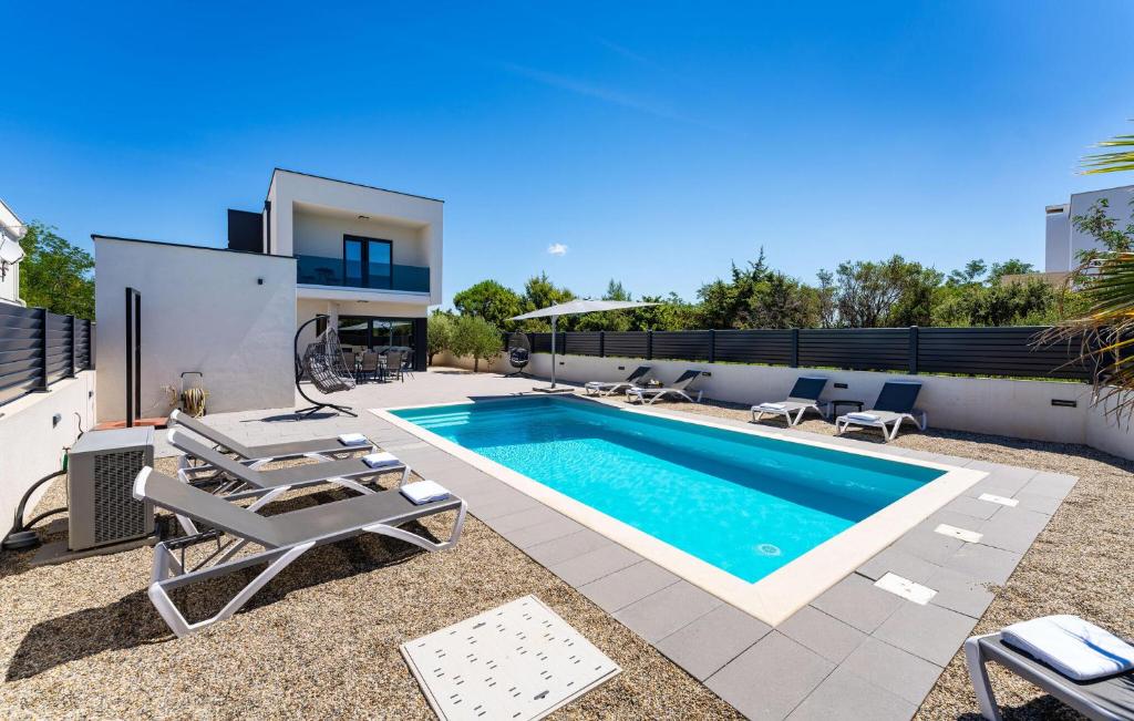 a swimming pool with chairs and a house at Villa Eclips in Zaton