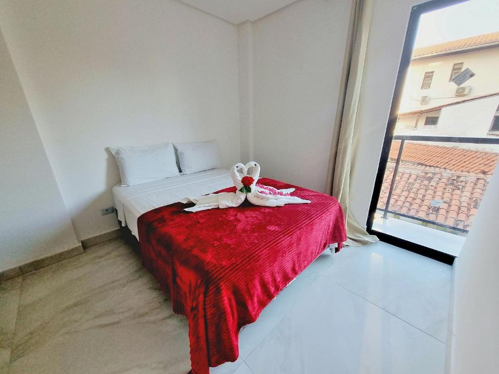 a bedroom with a bed with a red blanket at Ap no Coração de Porto de Galinhas Paulo Brito 101 - By Anfitrião Legal in Porto De Galinhas