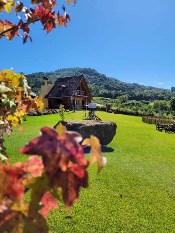 a house in the middle of a grassy field with a building at Cabana Canadense na serra gaúcha in São José do Hortêncio