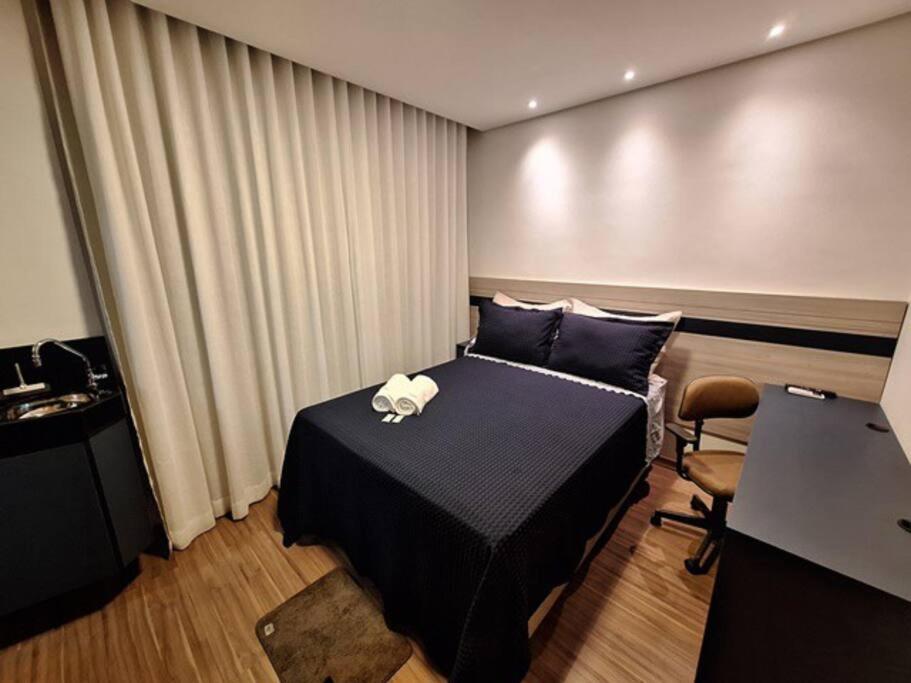 ein Schlafzimmer mit einem Bett, einem Schreibtisch und einem Stuhl in der Unterkunft Flat de luxo em Lagoa Santa in Lagoa Santa