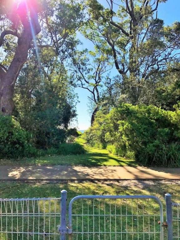 a fence in front of a field with trees at On Collingwood Beach by Book Jervis Bay - ON THE Bikepath TO Husky in Vincentia