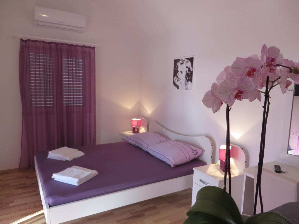 Un dormitorio con una cama con sábanas moradas y una planta en Apartments Petar, en Hvar