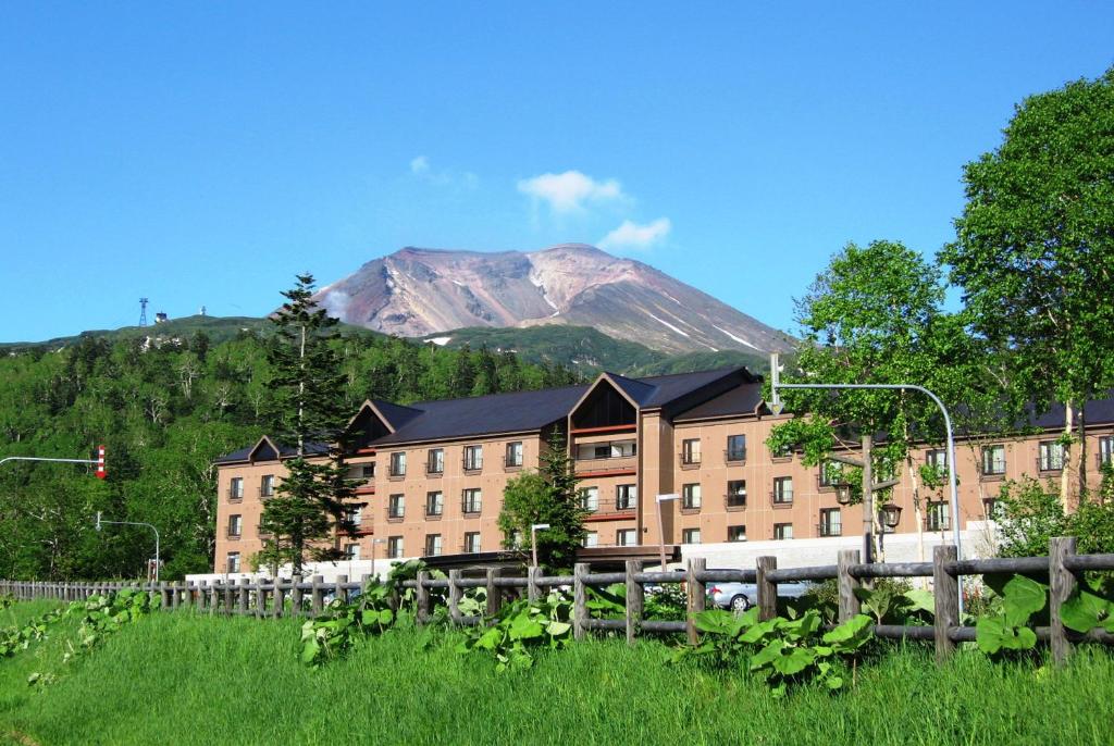 東川町にあるHigashikawa Asahidake Onsen Hotel Bear Monteの山を背景にした大きな建物
