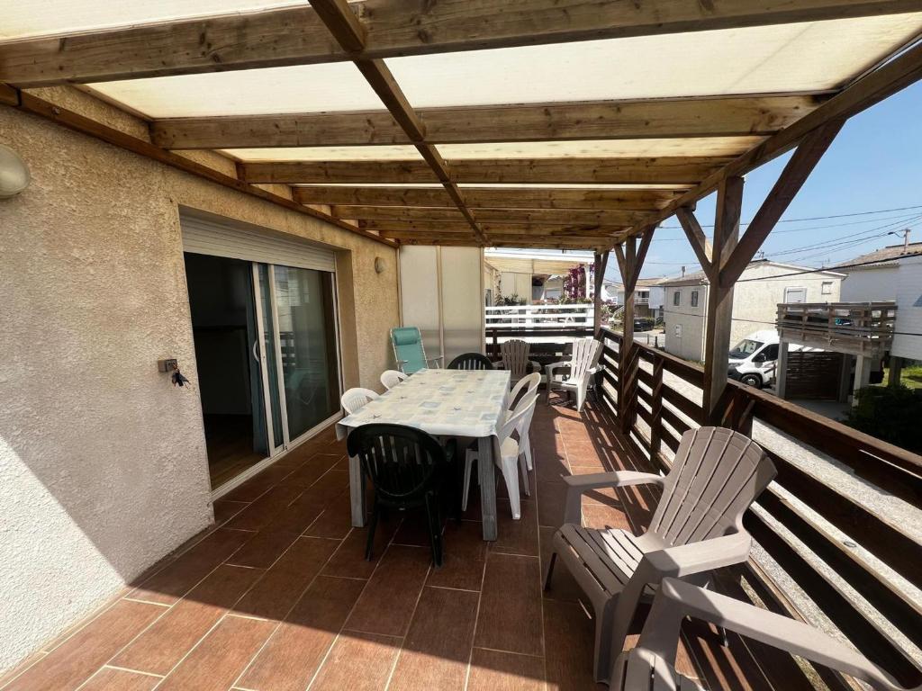 un patio avec une table et des chaises sur une terrasse dans l'établissement Chalet de 2 chambres à Gruissan - Terrasse, cuisine équipée, proche de la plage - FR-1-784-31, à Gruissan