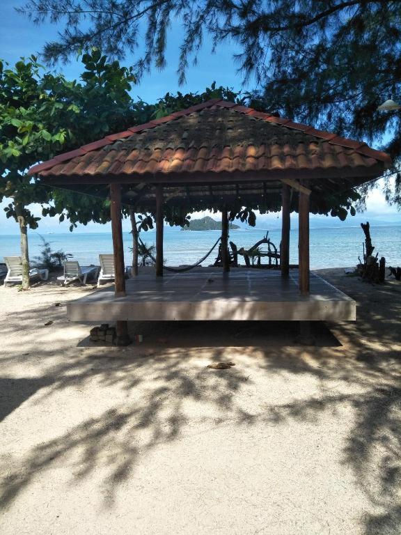 einen hölzernen Pavillon am Strand mit Meer in der Unterkunft Red Coral Cottage in Tanjung Rhu