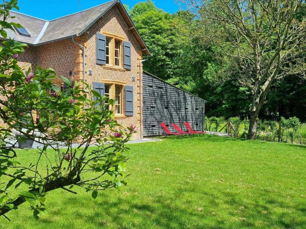 une maison en briques avec des chaises rouges dans une cour dans l'établissement Maison indépendante en lisière de bois avec jardin, vélos, baby-foot et cheminée près de Paris. - FR-1-532-20, à Fontenelle