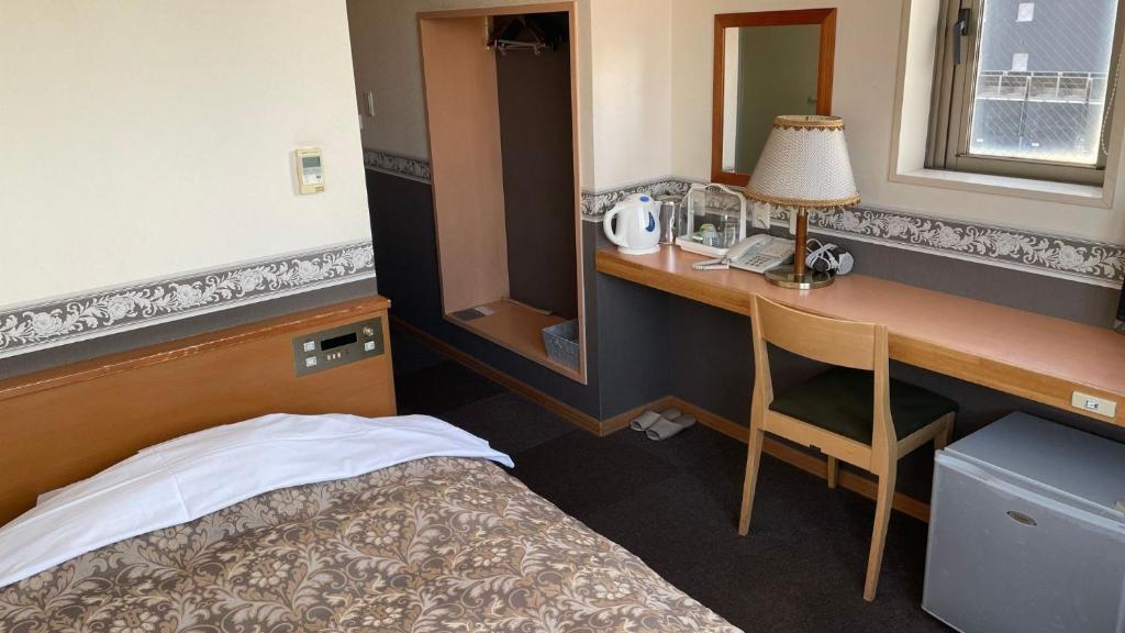 Zimmer mit einem Bett und einem Schreibtisch mit einer Lampe in der Unterkunft Hakodate Hotel Ekimae - Vacation STAY 91716v in Hakodate