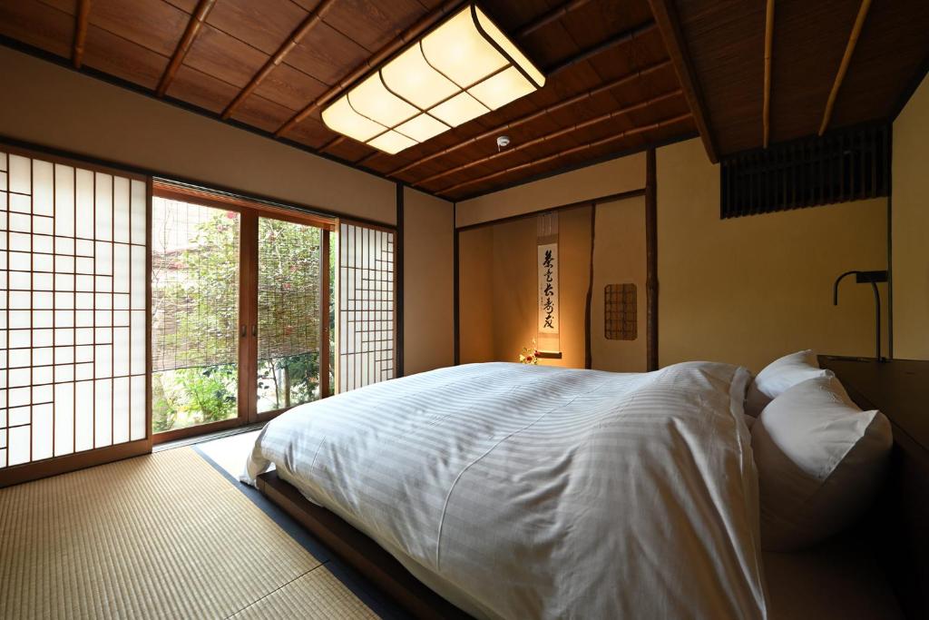 a bedroom with a bed and a large window at Oni no Sumika in Izu