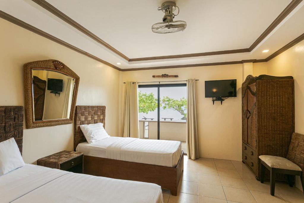 una camera d'albergo con due letti e uno specchio di Turtle Bay Dive Resort a Moalboal