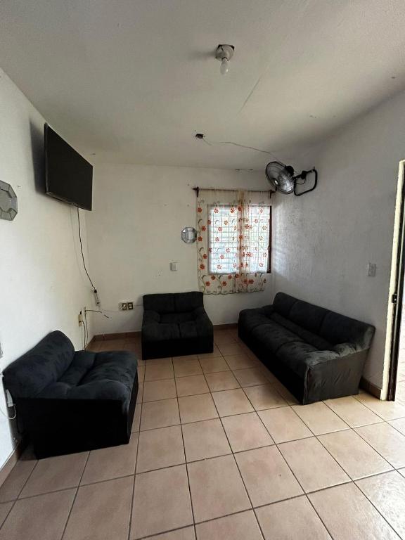 a living room with two black couches and a window at Casa Flor de Mayo in Santa Cruz Huatulco