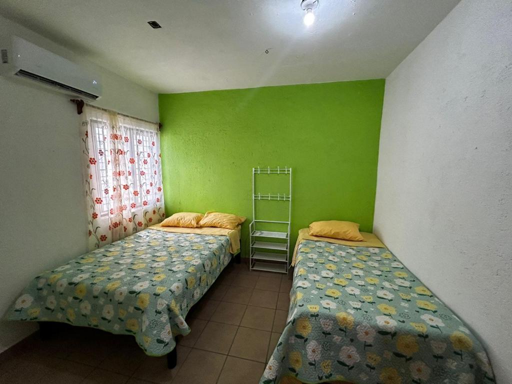 twee bedden in een kamer met groene muren bij Casa Flor de Mayo in Santa Cruz Huatulco