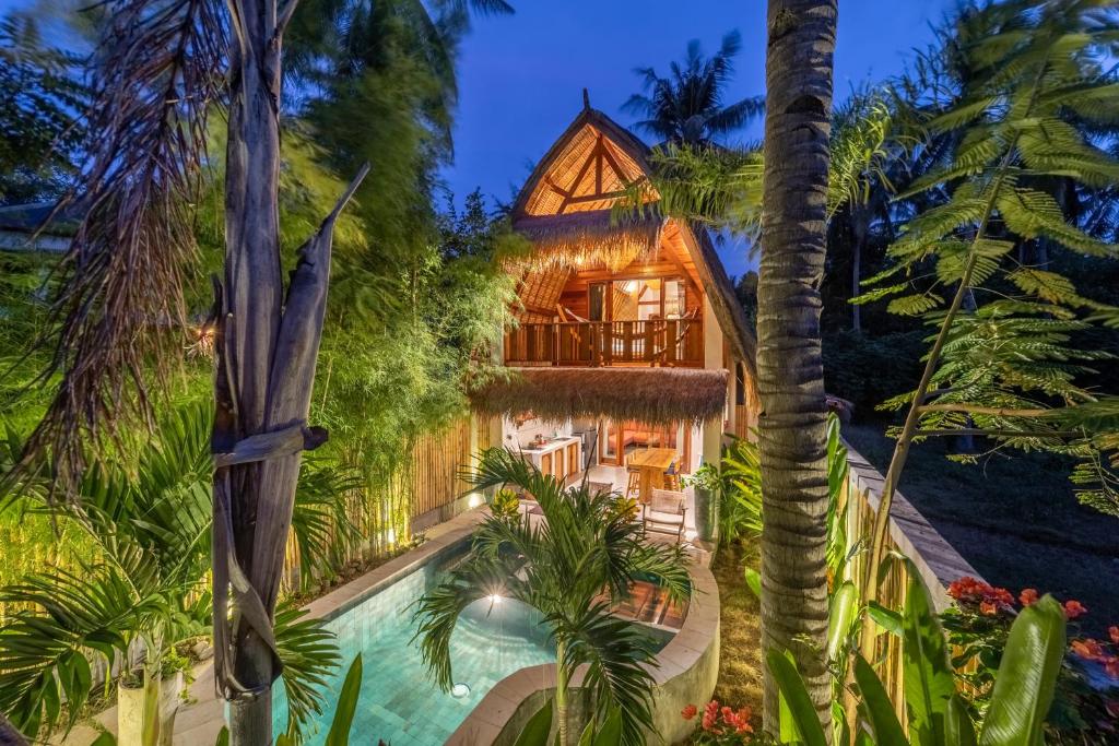 Vista exterior de una casa con piscina y palmeras. en La Villa Loca, en Gili Air