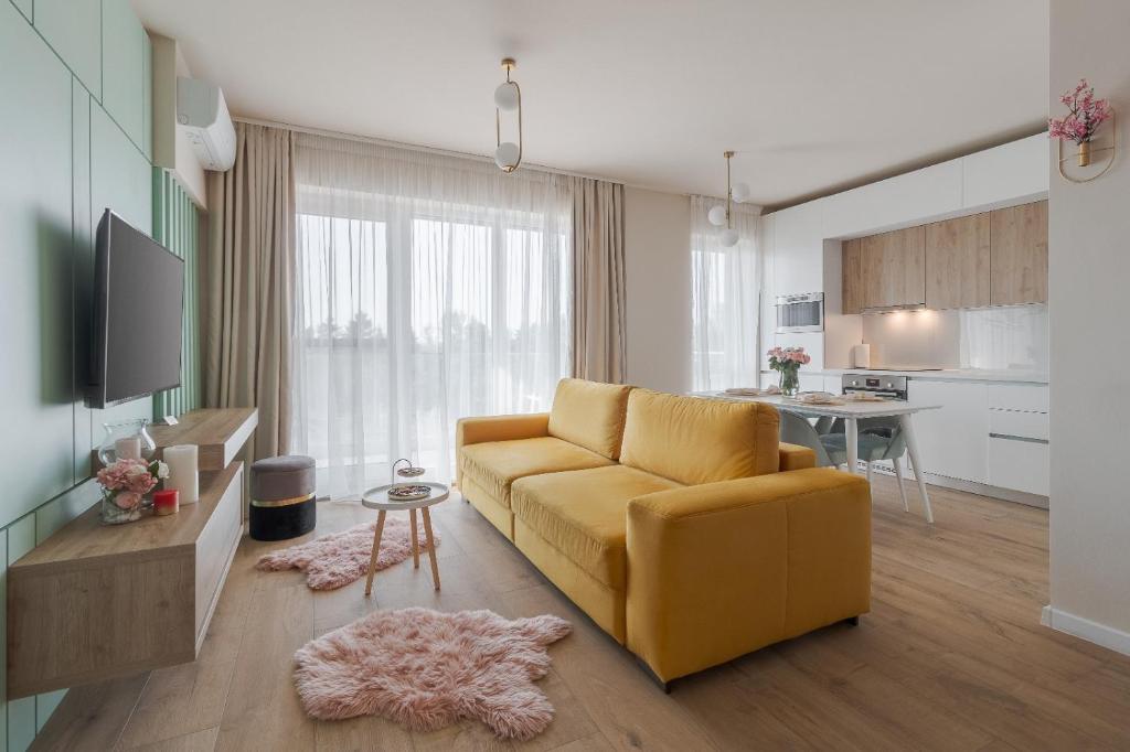a living room with a yellow couch and a kitchen at Chic Central Oradea in Oradea