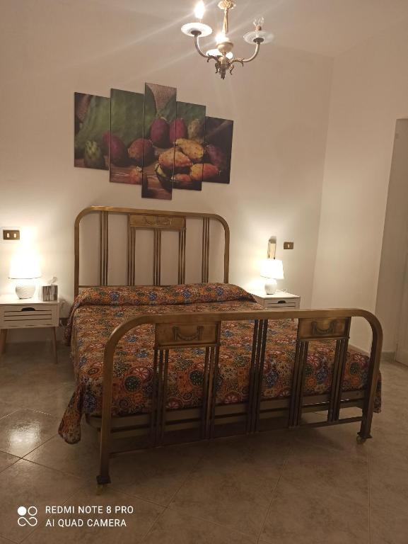 1 dormitorio con 1 cama con 2 mesas y 2 cuadros en Fico D'India, en Trapani