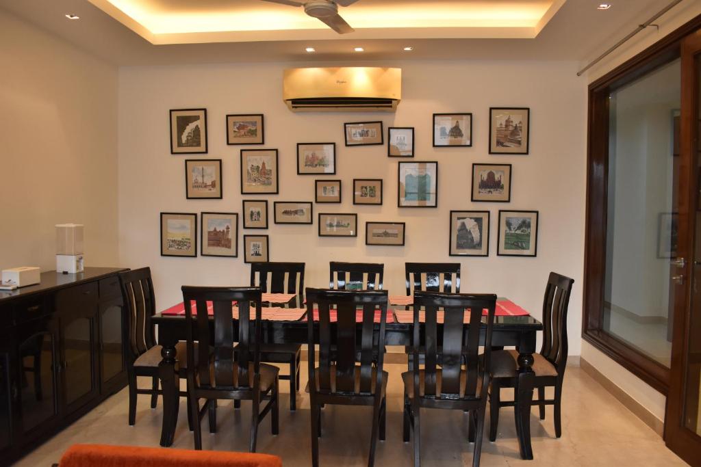 a dining room with a table and chairs and pictures on the wall at Two Green Park in New Delhi