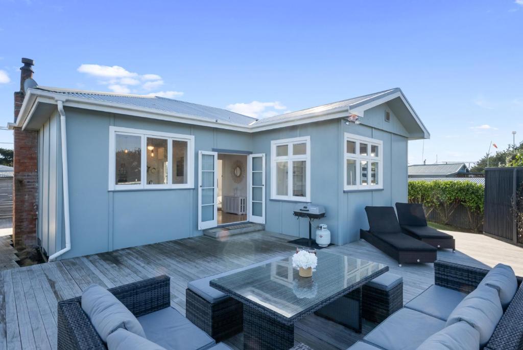 a blue house with a patio and a table at Ocean Breeze - Foxton Beach Holiday Home in Foxton