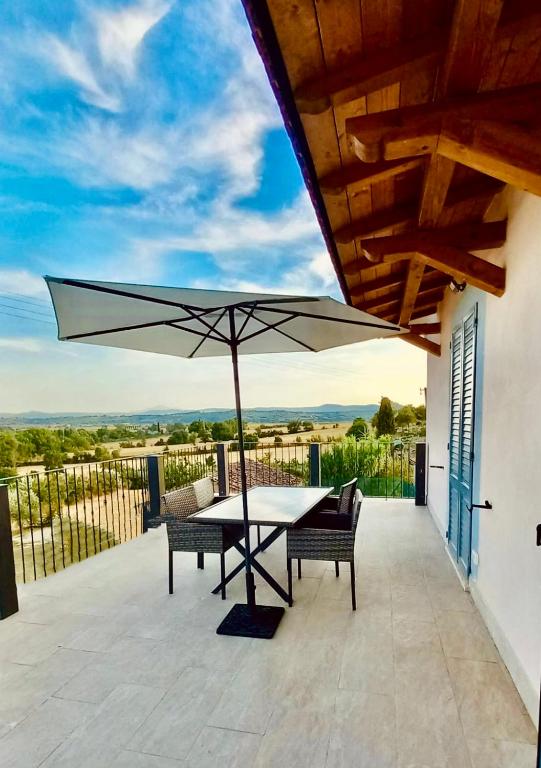 a patio with a table and chairs and an umbrella at Bellavista La Querce in Foiano della Chiana