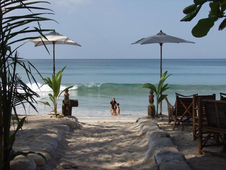 eine Gruppe von Menschen am Strand mit einem Sonnenschirm in der Unterkunft JJ Beach Resort & JJ Seafood in Ko Phayam