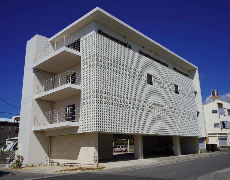 un edificio de apartamentos blanco con fachada blanca en 島の宿 Amanzaーアマンツァー, en Ishigaki Island