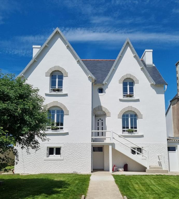 une maison blanche avec un ciel bleu en arrière-plan dans l'établissement Maison de charme avec vue mer et jardin, à Plouhinec