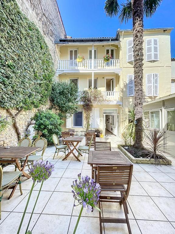 Un patio con mesas y sillas y un edificio. en The Originals Boutique, Hôtel Roca-Fortis, Rochefort, en Rochefort